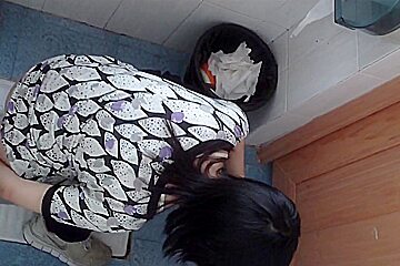 Dark-haired Asian babe pissing in the public toilet