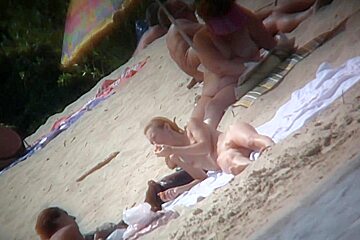 Naked woman with trimmed pussy likes to relax on the beach